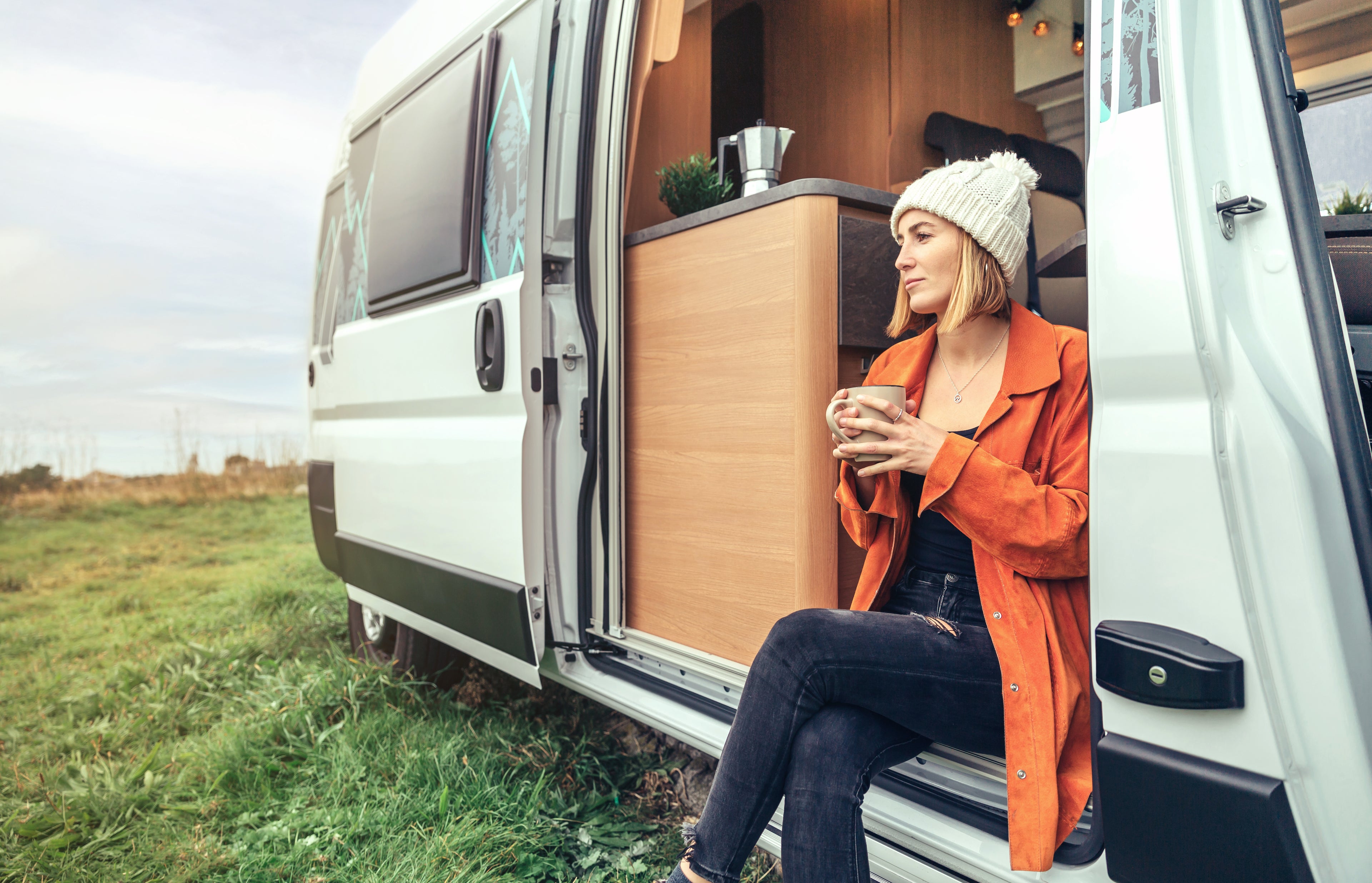 Frau sitzt im Camper mit Tasse
